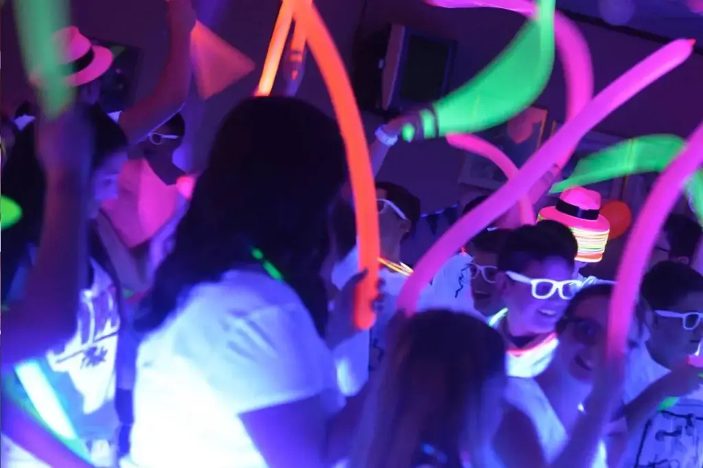 Soundwaves Event Group DJ creating a packed dance floor at a Pittsburgh glow-in-the-dark birthday party with balloons, hats, and glowing accessories
