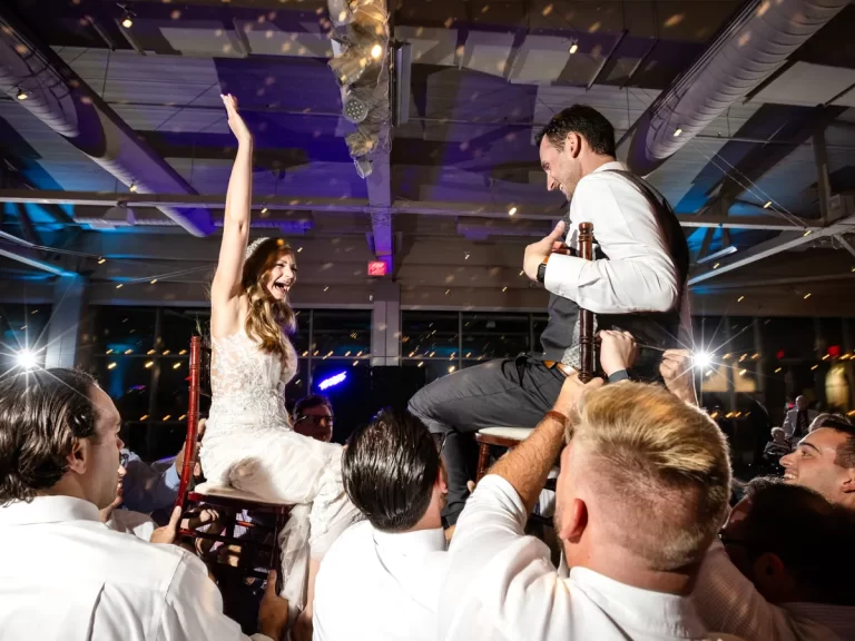 Bride and groom lifted in chairs on a packed dance floor at a Pittsburgh wedding reception at the Heinz History Center