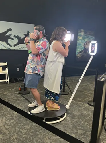 Two wedding guests dancing with drinks while using the SWEG 360 photo booth at a Pittsburgh wedding