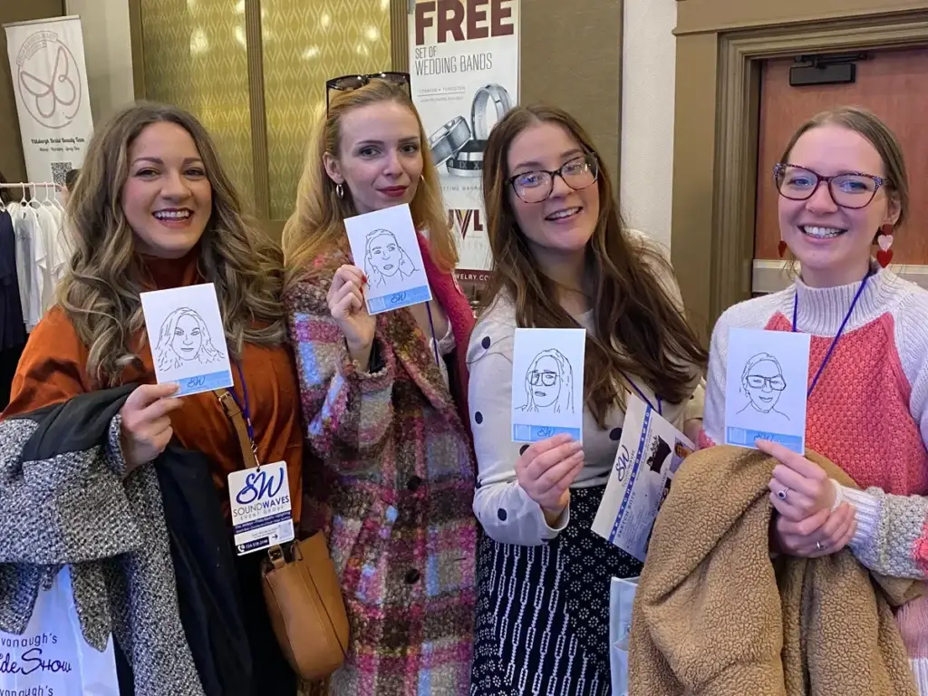 Four guests holding Sketch Bots photos at Pittsburgh bridal show