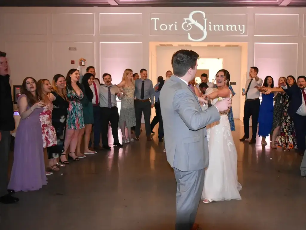 Bride and groom sharing their last dance surrounded by guests singing in a circle with a custom monogram at The Audrey wedding reception